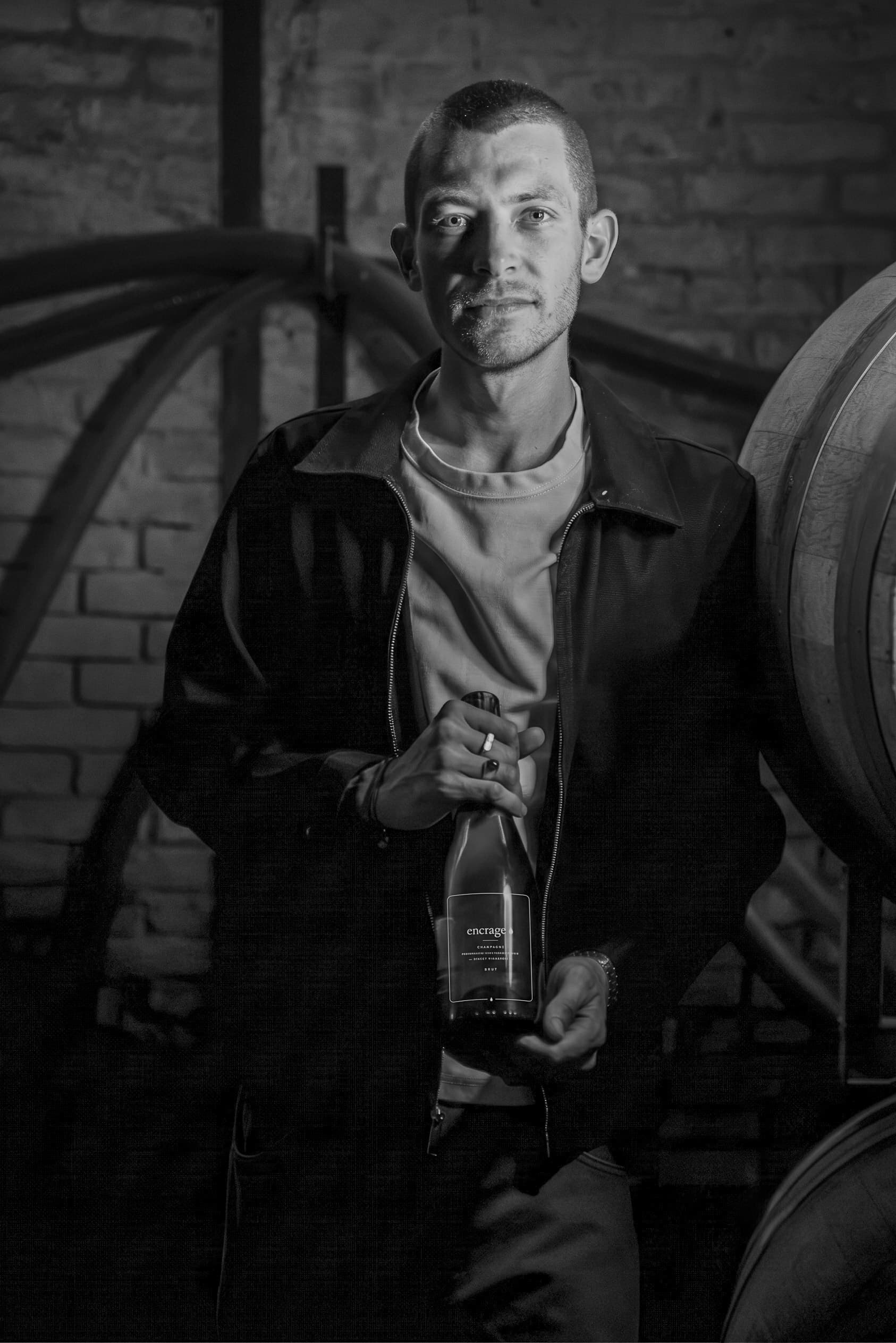 Baptiste, fondateur d'Encrage, une bouteille à la main, en cave